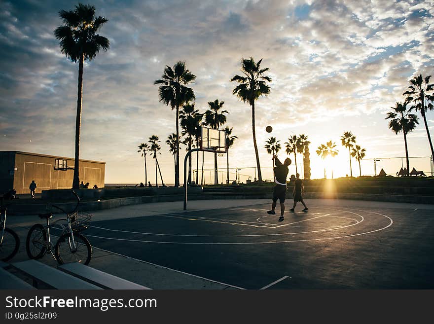 Kids playing basketball on a court at sunset. Kids playing basketball on a court at sunset.