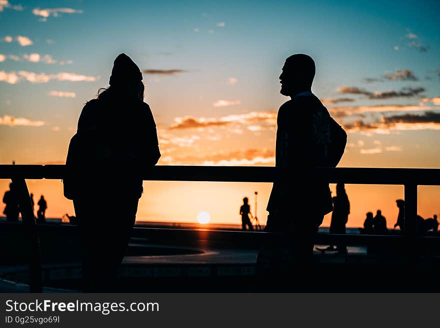 Couple seen in silhouette possibly watching a game of golf at sunset, golden sky and fluffy cloud. Couple seen in silhouette possibly watching a game of golf at sunset, golden sky and fluffy cloud.