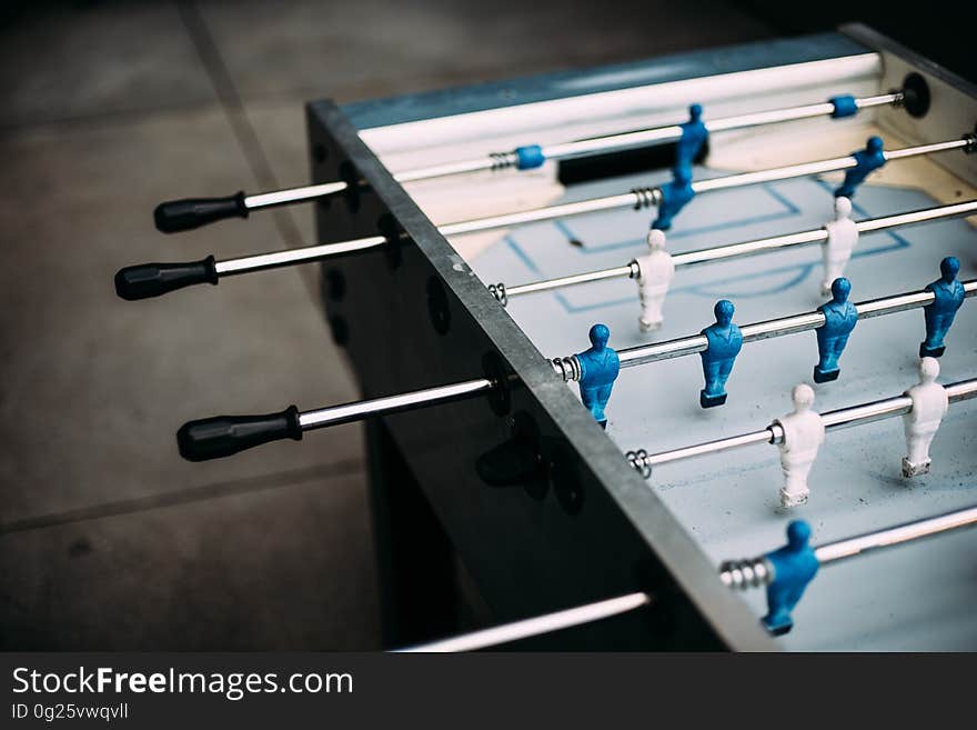 Unoccupied foosball table with blue and white men.