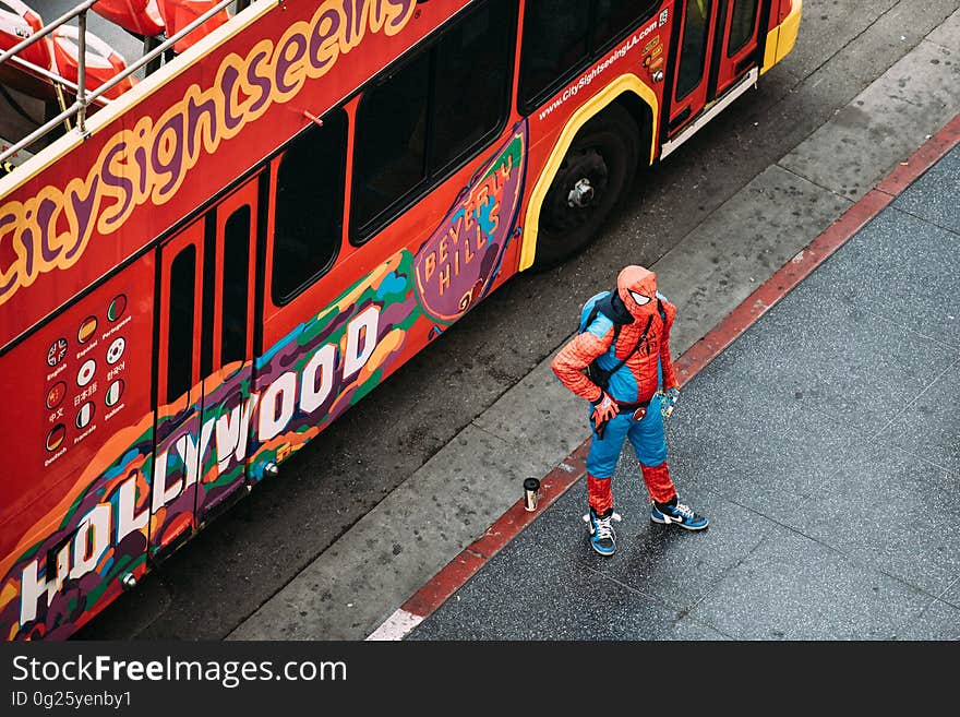 Man in spiderman costume standing next to Hollywood sightseeing bus on street. Man in spiderman costume standing next to Hollywood sightseeing bus on street.