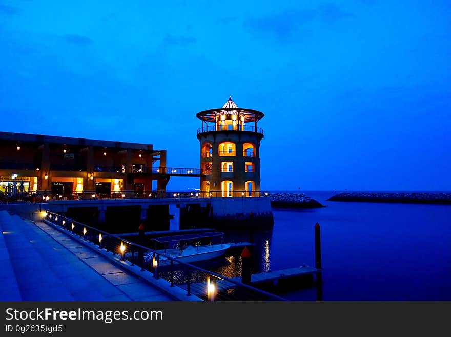 Ocean pier and docks illuminated at night with round tower and blue tone. Ocean pier and docks illuminated at night with round tower and blue tone.