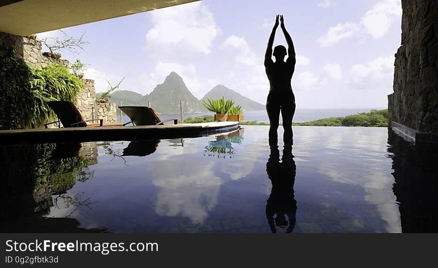 A person standing at poolside in a tropical resort. A person standing at poolside in a tropical resort.