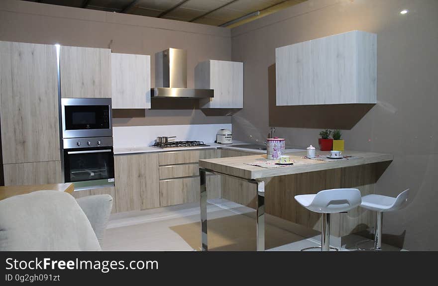 Modern kitchen diner in small flat or apartment, with sink, microwave, oven, cooker, table and chairs, cupboard, extractor fan, hood, looking clean and smart. Modern kitchen diner in small flat or apartment, with sink, microwave, oven, cooker, table and chairs, cupboard, extractor fan, hood, looking clean and smart.