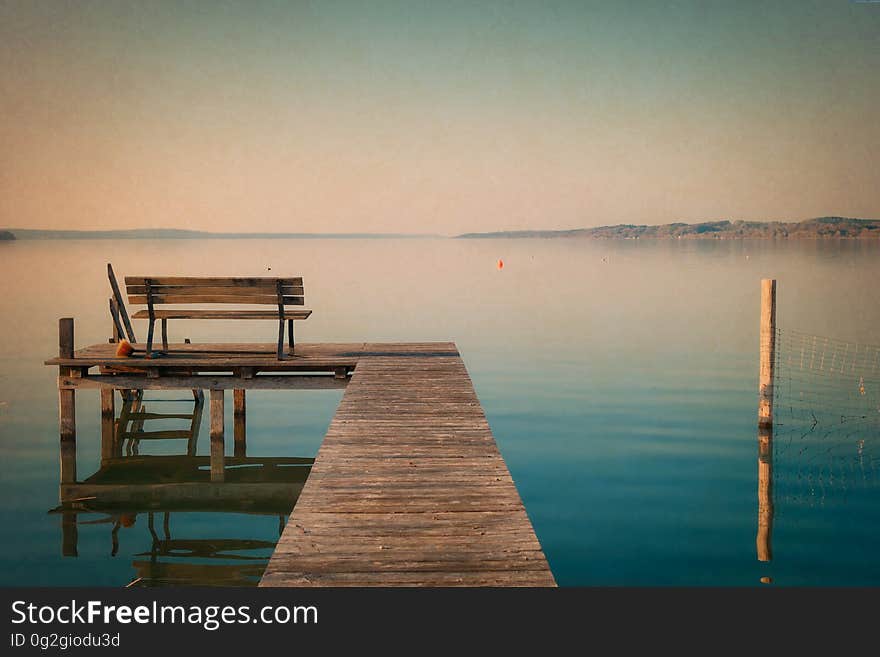 Wooden bench on dock along waterfront as sunset. Wooden bench on dock along waterfront as sunset.