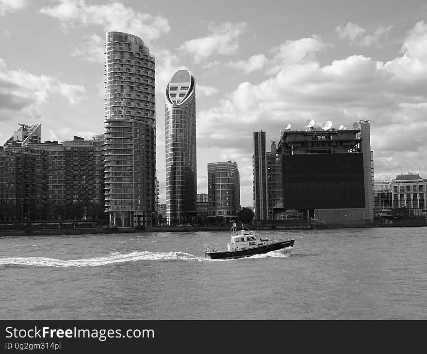 Boat in river passing urban waterfront skyline with skyscrapers in black and white. Boat in river passing urban waterfront skyline with skyscrapers in black and white.