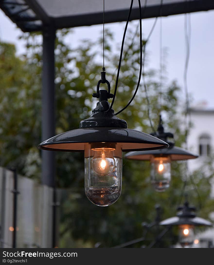 Clear glass bulbs in metal lamps illuminated in outdoors. Clear glass bulbs in metal lamps illuminated in outdoors.