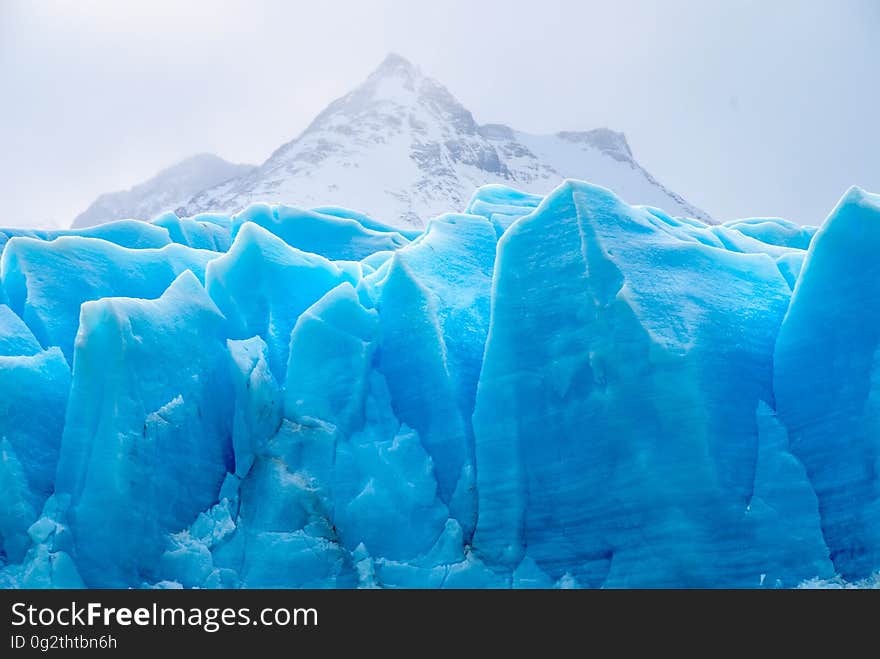 Close up of blue glacial ice in mountains against cloudy or overcast skies.