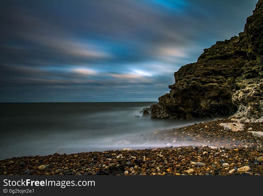 Rocky beach next to cliff along waterfront at sunset. Rocky beach next to cliff along waterfront at sunset.