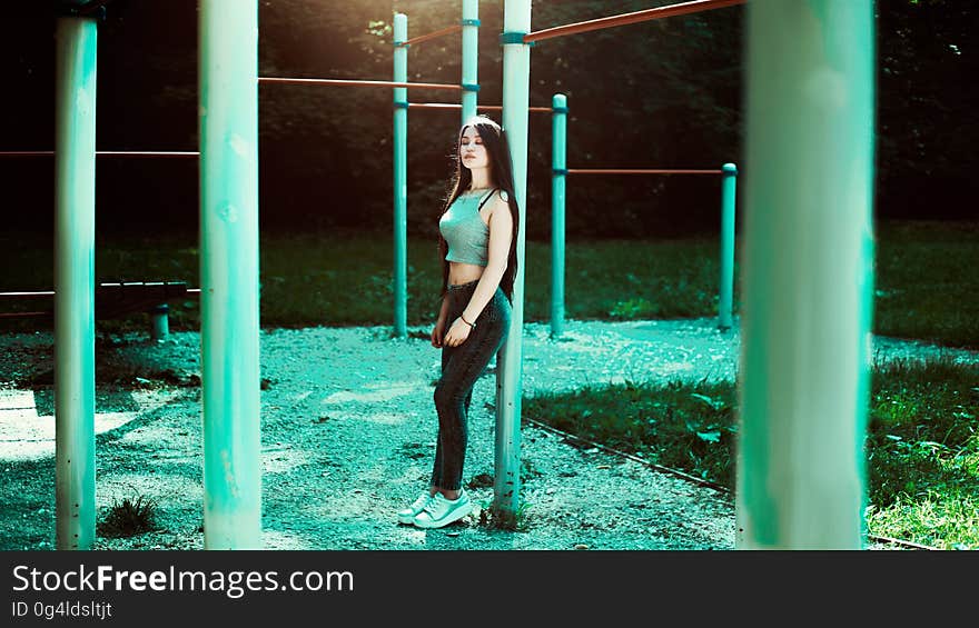 Portrait of young woman in blue jeans and grey top outdoors in jungle gym. Portrait of young woman in blue jeans and grey top outdoors in jungle gym.