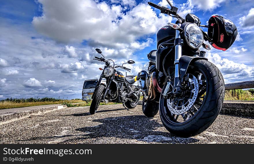 Motorcycles on road in countryside with blue skies and clouds.