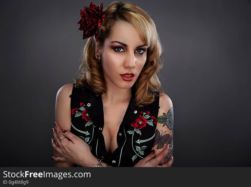 Woman in Black Red and Green Floral Sleeveless Shirt With Red Flower on Her Head and Butterfly Tattoo on Her Left Arm