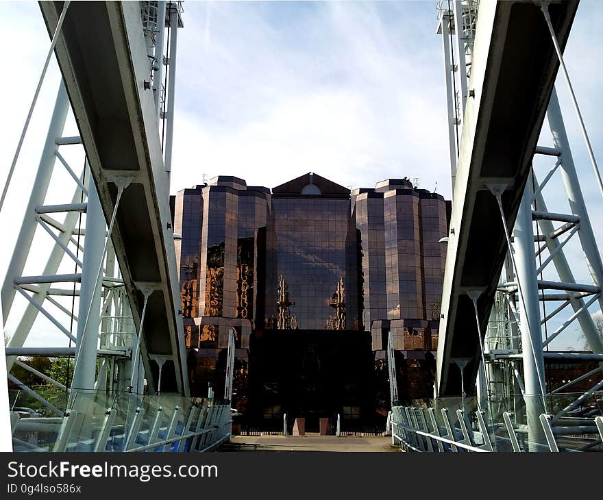 A view from a bridge at a building with reflective panels on the wall. A view from a bridge at a building with reflective panels on the wall.