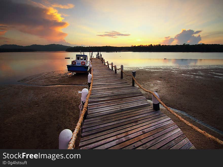 A wooden pier with boat docket at sunset. A wooden pier with boat docket at sunset.