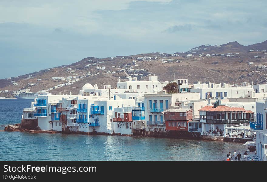 White houses along waterfront of Mykonos, Greece on sunny day.