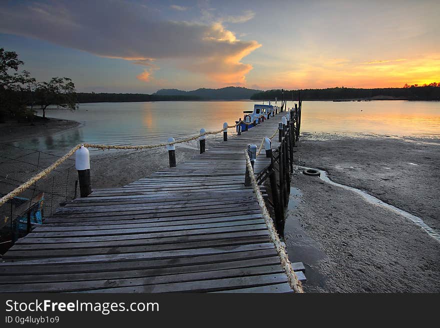 Wooden pier jetting into water along shores at sunset. Wooden pier jetting into water along shores at sunset.