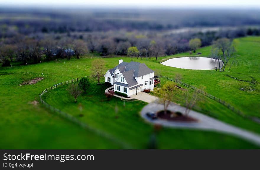 Aerial view of white house in green field in countryside on sunny day. Aerial view of white house in green field in countryside on sunny day.