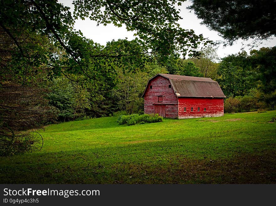 Barn in the Middle of Lawn Surrounded With Trees during Daytime