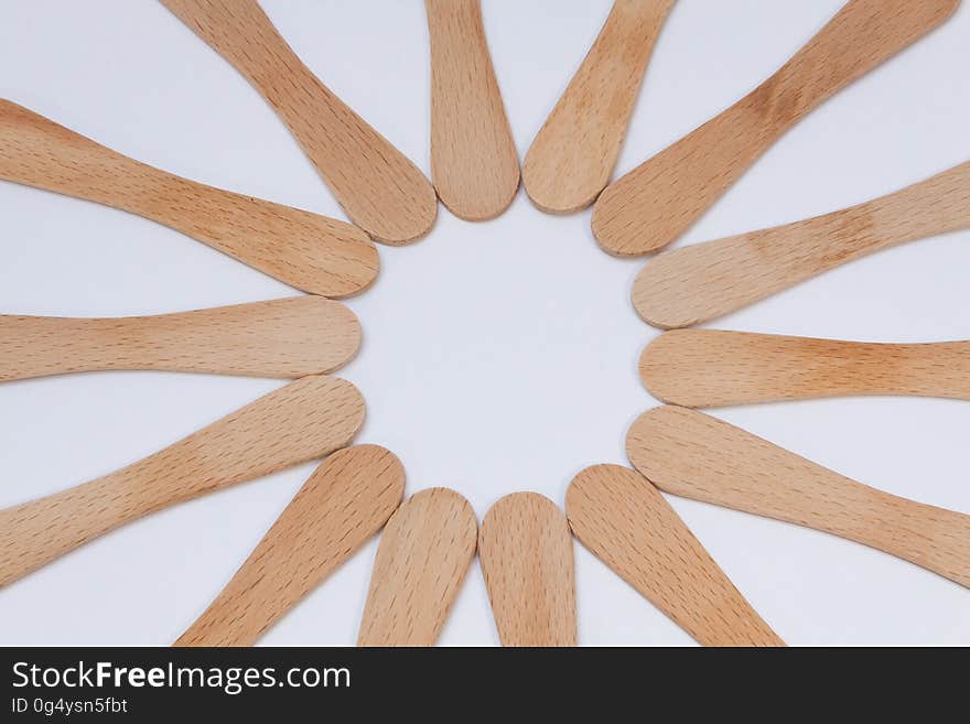 Plain wooden spoons in circle on white.