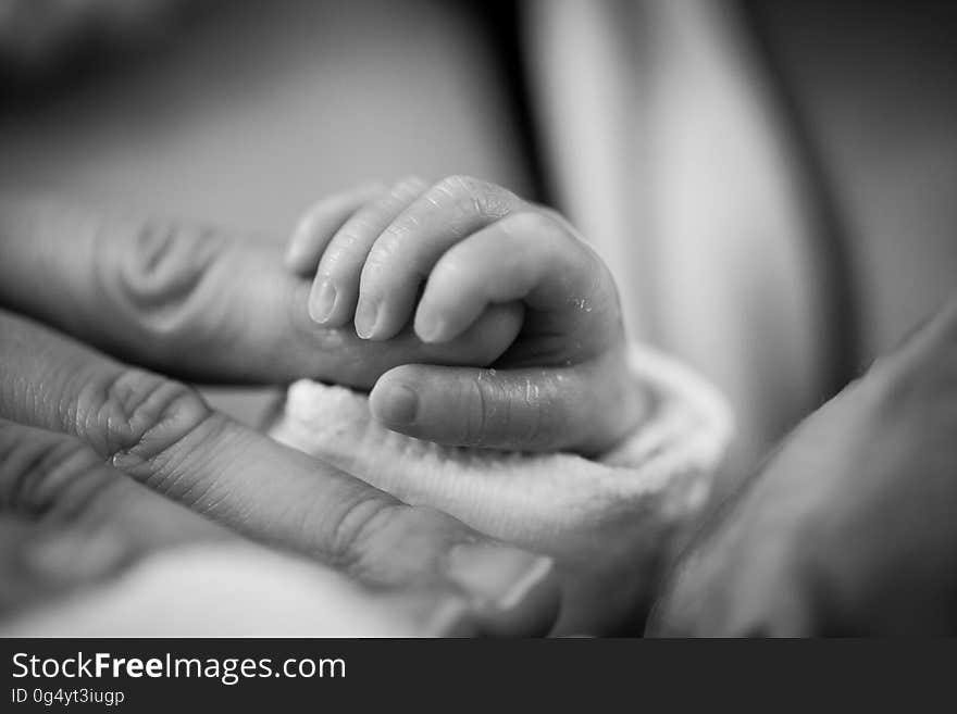 Grayscale Photography of Baby Holding Finger