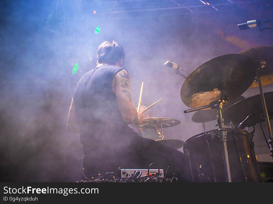 A man playing drums in a concert. A man playing drums in a concert.