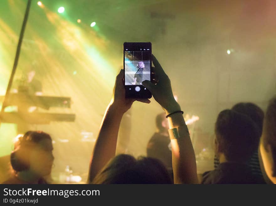 A man taking a photo of the musicians at a concert. A man taking a photo of the musicians at a concert.