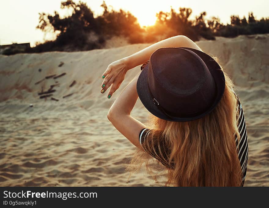 A young woman with a hat on a sandy beach looking at the morning sun. A young woman with a hat on a sandy beach looking at the morning sun.