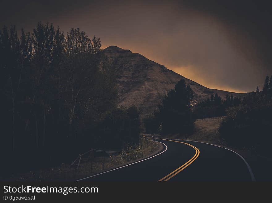 An empty curving mountain road in the evening.
