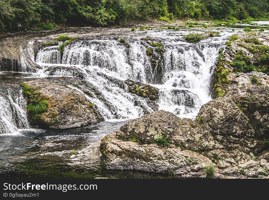 Water in stream over rocks creating rapids on sunny day. Water in stream over rocks creating rapids on sunny day.