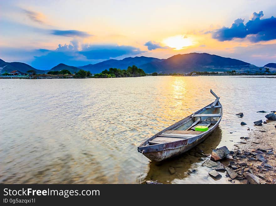 Wooden boat on shoreline of lake in mountains at dawn. Wooden boat on shoreline of lake in mountains at dawn.