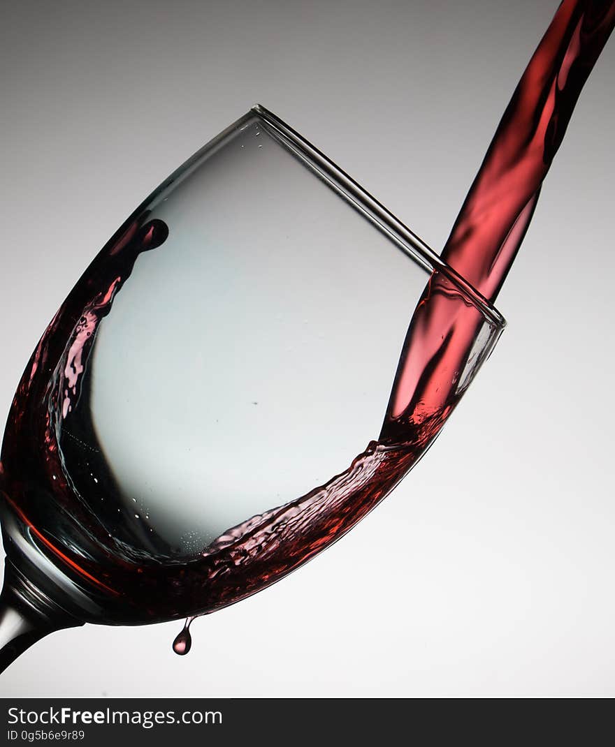 A close up of red wine pouring into a glass. A close up of red wine pouring into a glass.