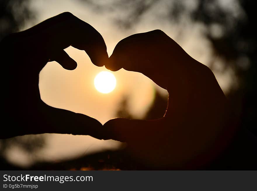 Silhouette of Person Hand Doing Heart Shape during Sunset