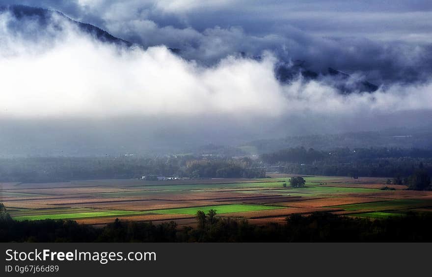 Landscape Photography of Green and Brown Rice Field Surrounded With White and Blue Clouds Near Black Mountains