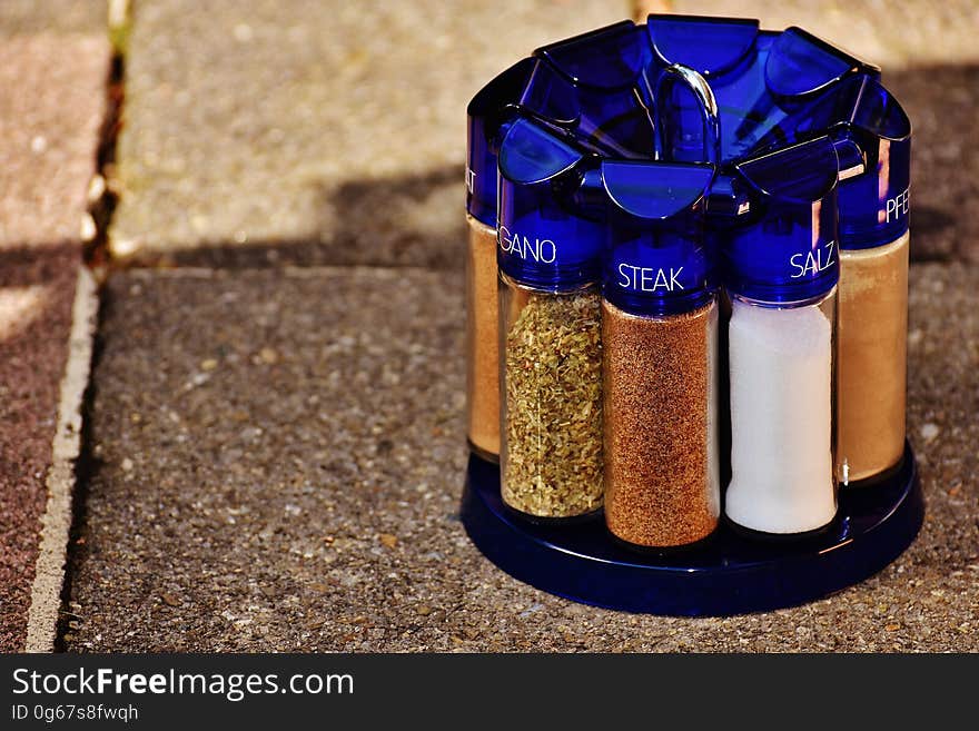 Clear tubes of seasonings with blue caps in rack outside on paving stones. Clear tubes of seasonings with blue caps in rack outside on paving stones.