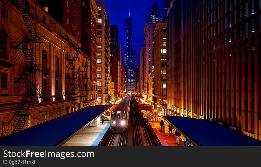 Train at platform in city illuminated at night. Train at platform in city illuminated at night.