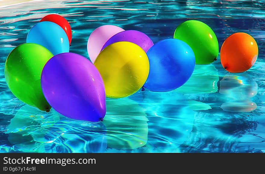 Purple Yellow and Blue Balloon on Swimming Pool