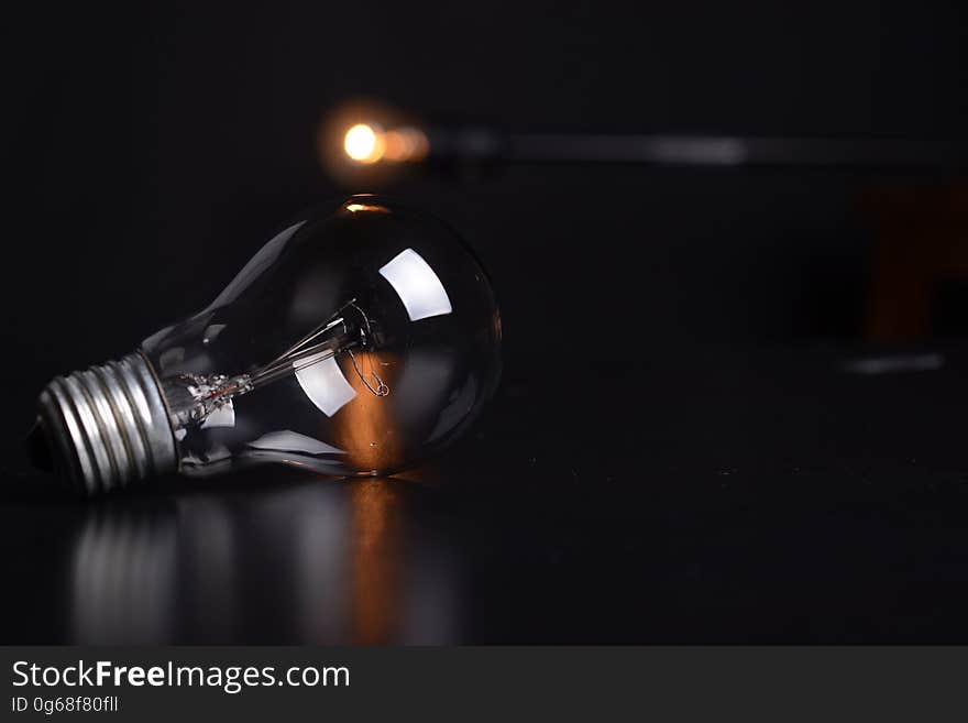 Close up of clear glass light bulb on tabletop with spotlight. Close up of clear glass light bulb on tabletop with spotlight.