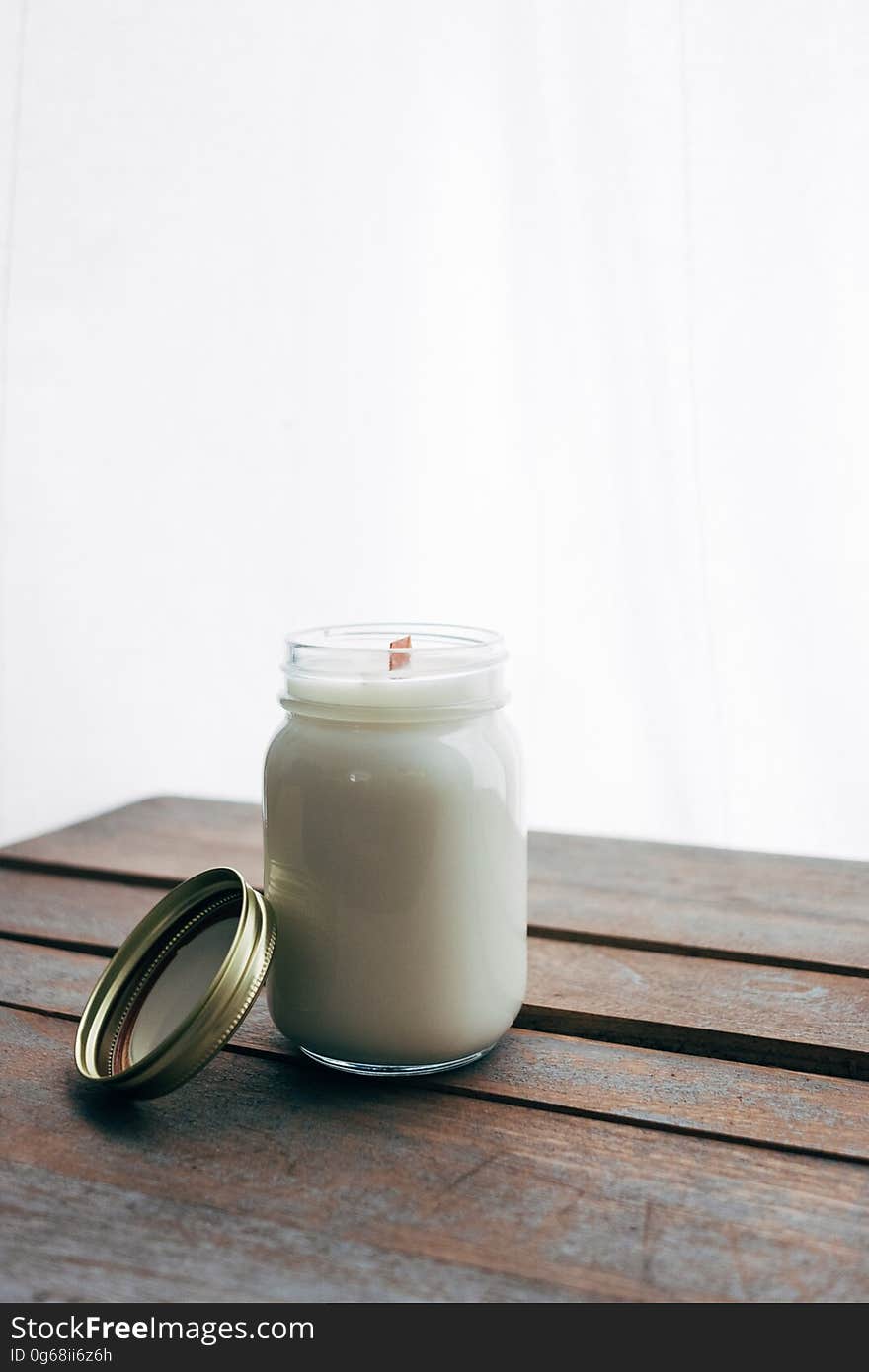 A close up of an open jar of sugar on a wooden table.