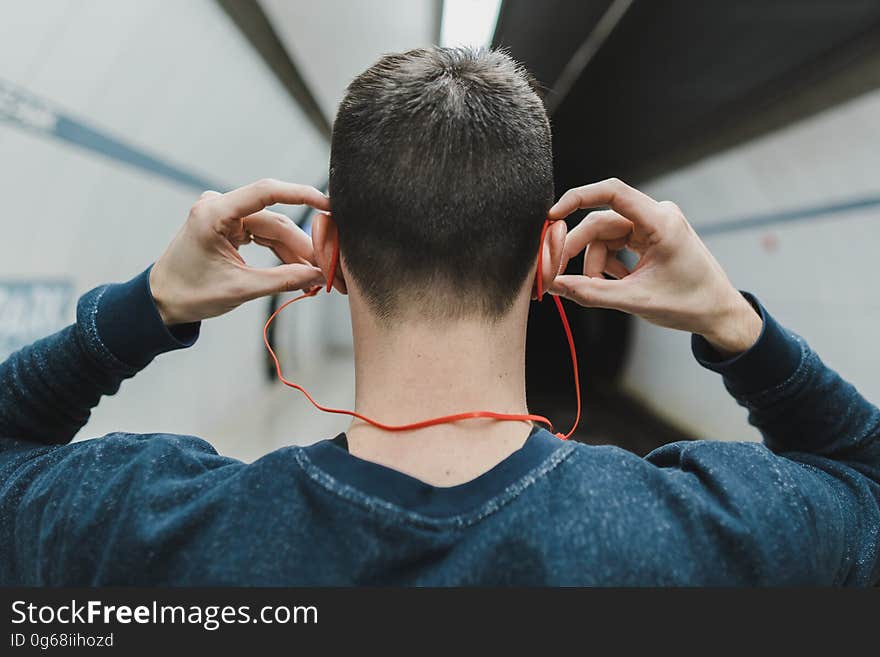 A back portrait of a young man in the subway putting earphones in his ears. A back portrait of a young man in the subway putting earphones in his ears.