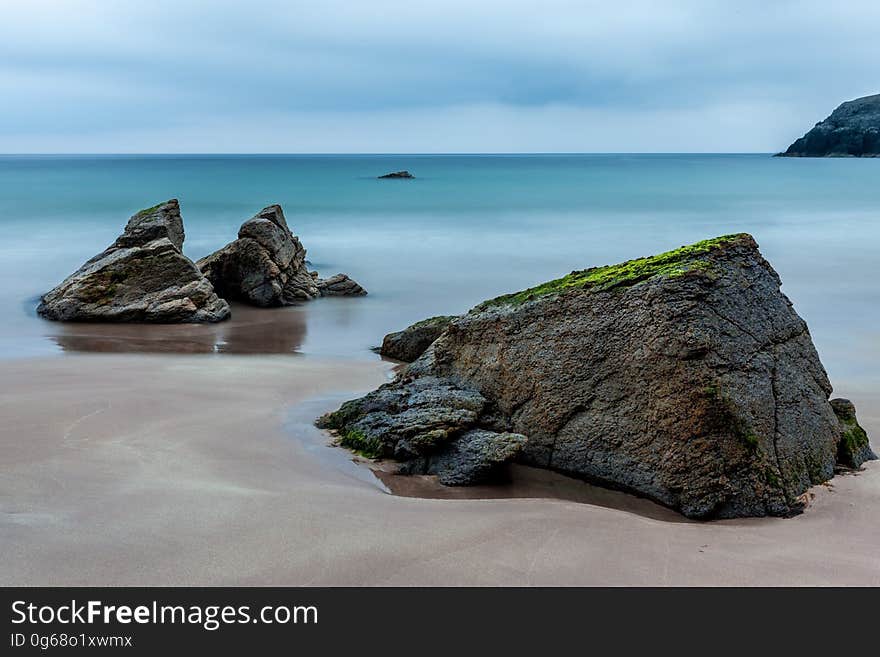 3 Brown Boulders on Seashore during Daytime