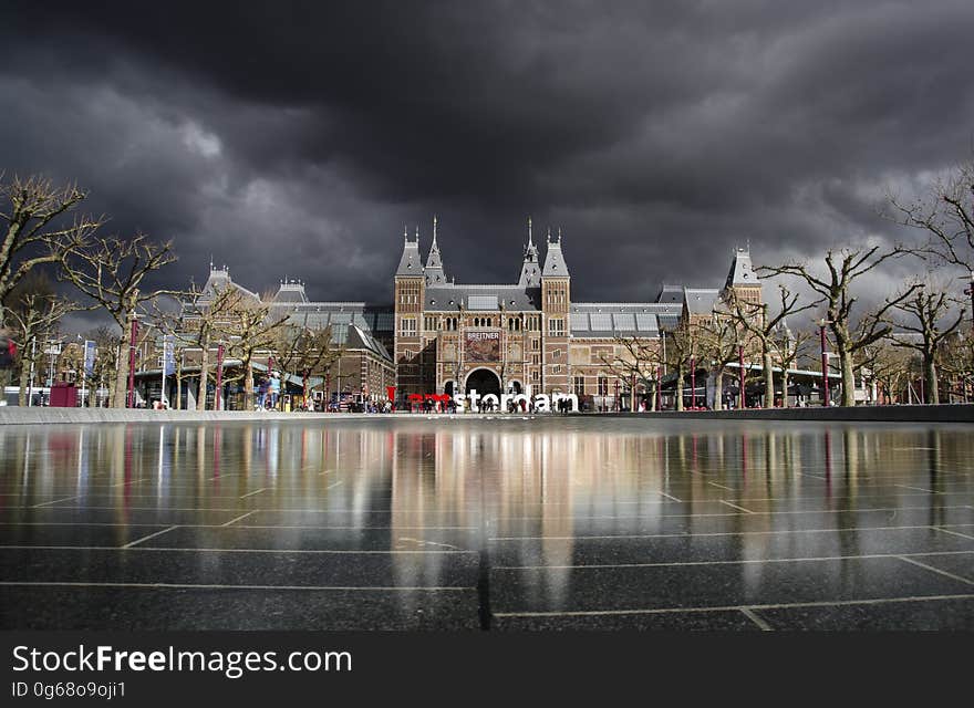 Brown and Grey High Rise Building Beside Leafless Trees during Dark Skies