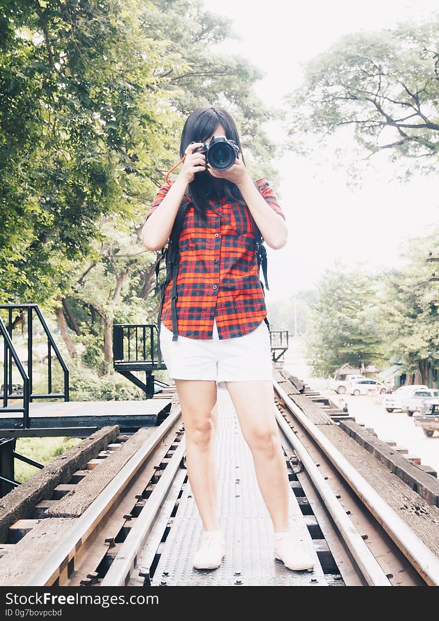 Happy asian woman on vacation photographing with a dslr camera on railway in forest