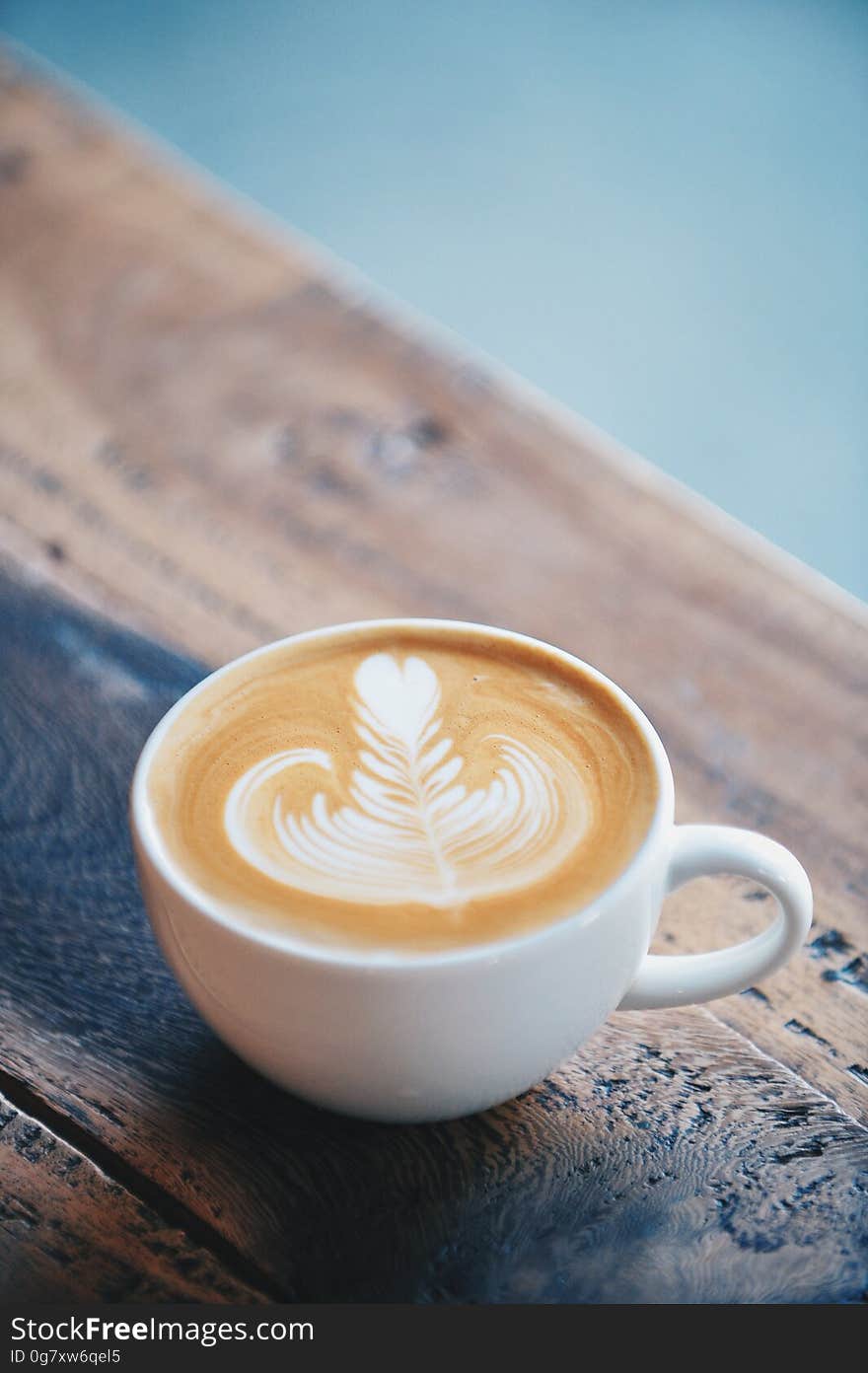 A close up of a cup of espresso with milk on a wooden table.