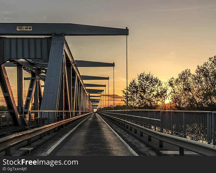 Tracks over old railroad bridge against orange skies at sunset. Tracks over old railroad bridge against orange skies at sunset.