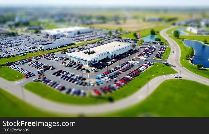 Modern manufacturing factories with extensive car parking and parked cars. The buildings are on a green field site with access roads, lake and selective focus on the nearest building. Modern manufacturing factories with extensive car parking and parked cars. The buildings are on a green field site with access roads, lake and selective focus on the nearest building.