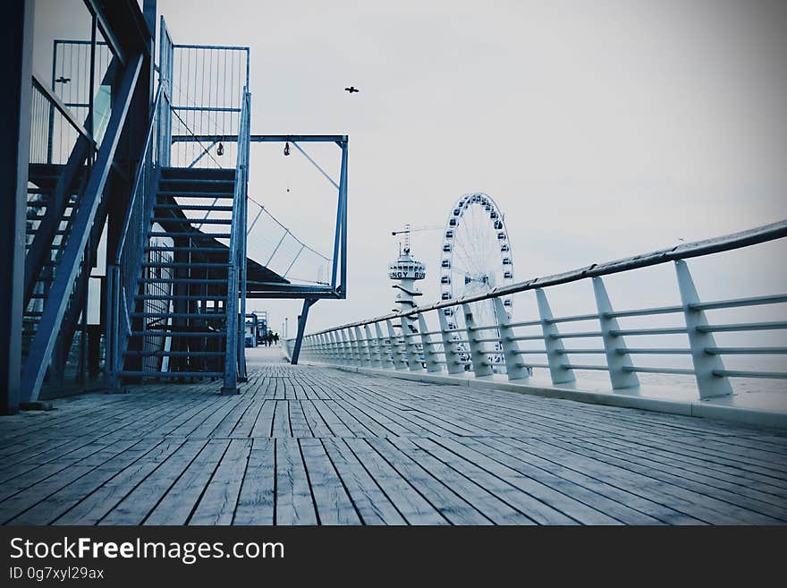 A boardwalk with railing and staircase and a Ferris wheel in the background. A boardwalk with railing and staircase and a Ferris wheel in the background.