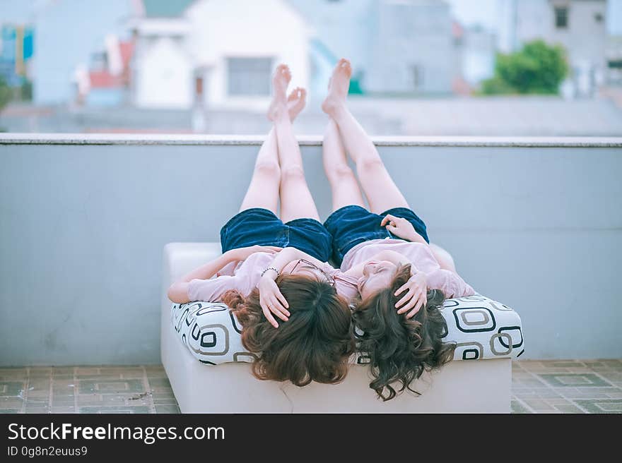 Twin girls laying outdoors on twin beds in urban setting. Twin girls laying outdoors on twin beds in urban setting.