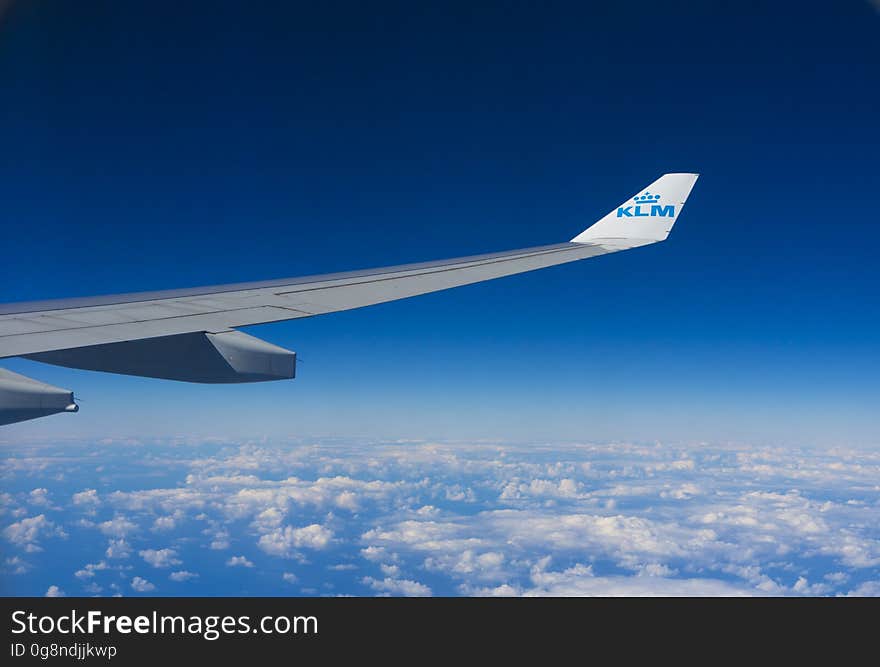 An airplane wing and white clouds below it.