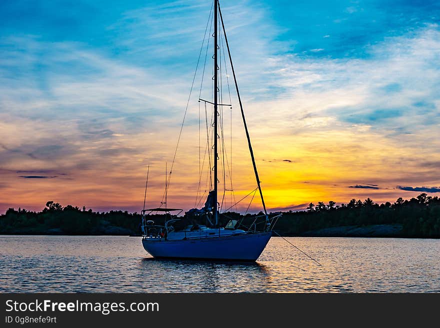 A sailboat in the sea at sunset. A sailboat in the sea at sunset.