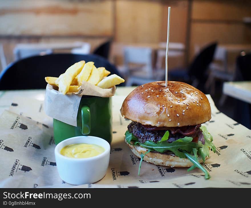 A burger with French fries and a dip on a table.