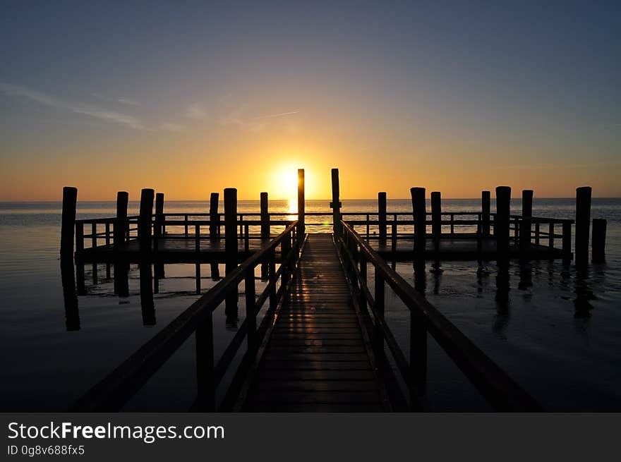 A silhouetted wooden pontoon at sunset.